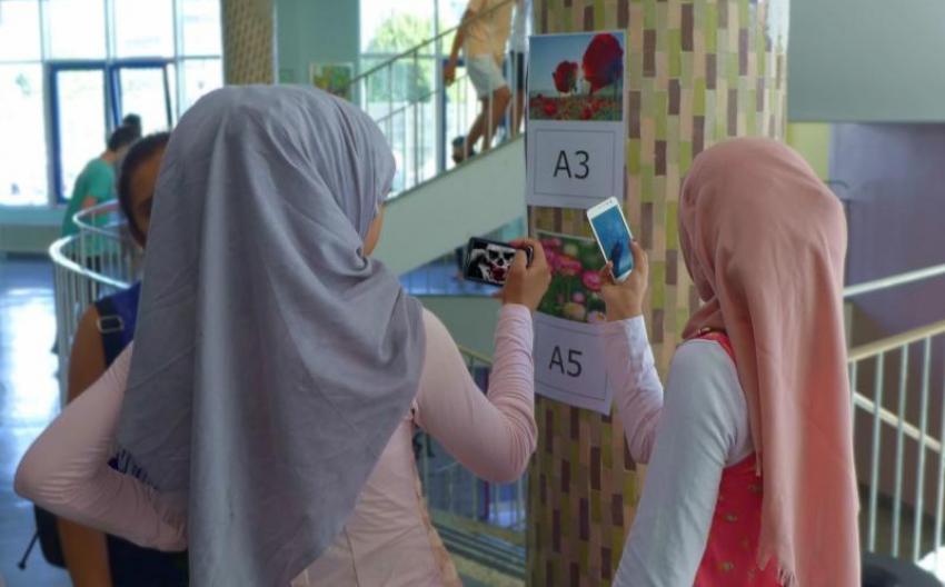 schul-stiegenhaus, zwei jugendliche schauen auf smartphone, markierung an der wand
